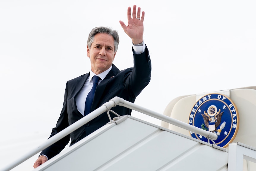 Man waves while disembarking from airplane.