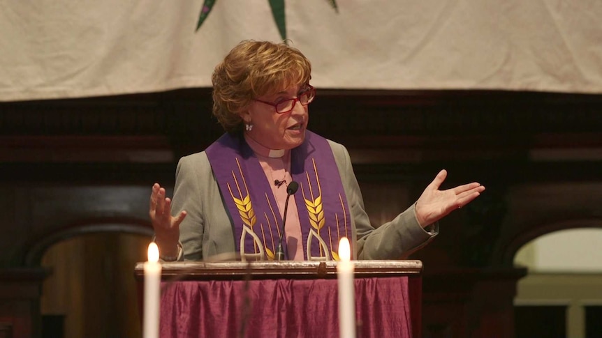 Jo Inkpin stands behind a wooden lectern, speaking.