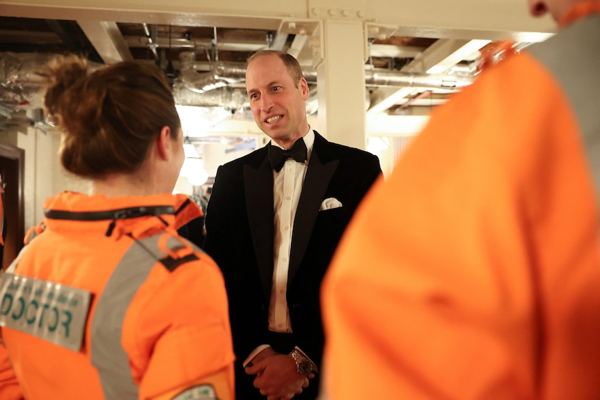 Prince William in tuxedo talks to doctors in hi-vis 