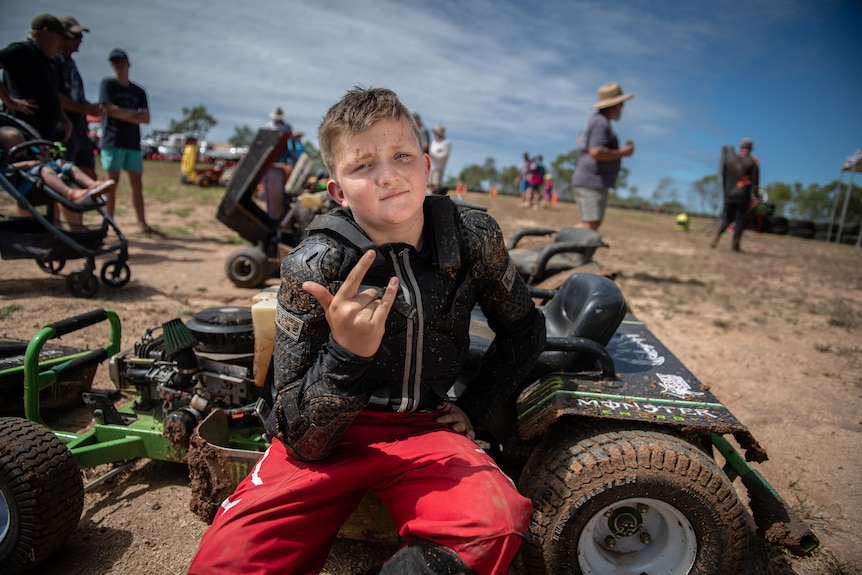 Ten-year-old Sean Twaddell sits on a lawnmower that has been modified for racing on a dirt track
