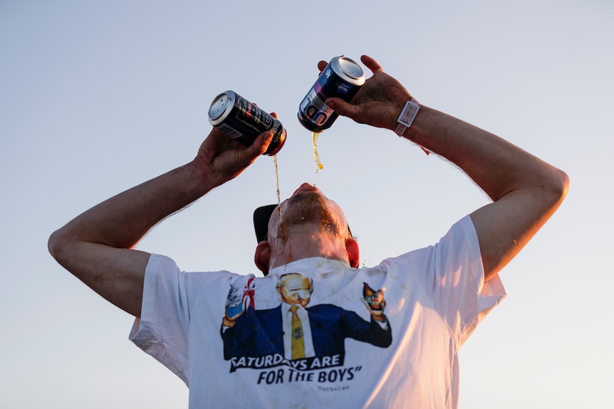 A man downs two cans of alcoholic drinks at once.