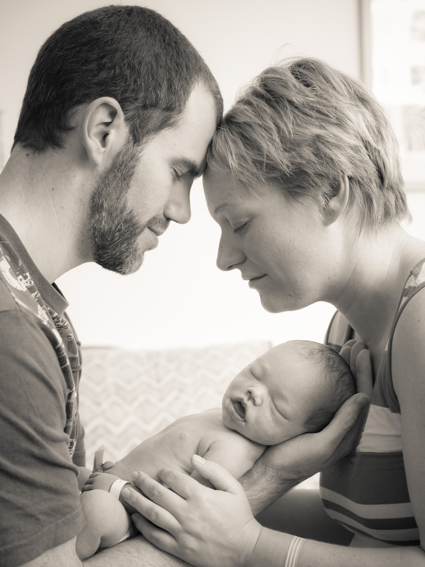 A woman and man holding a baby