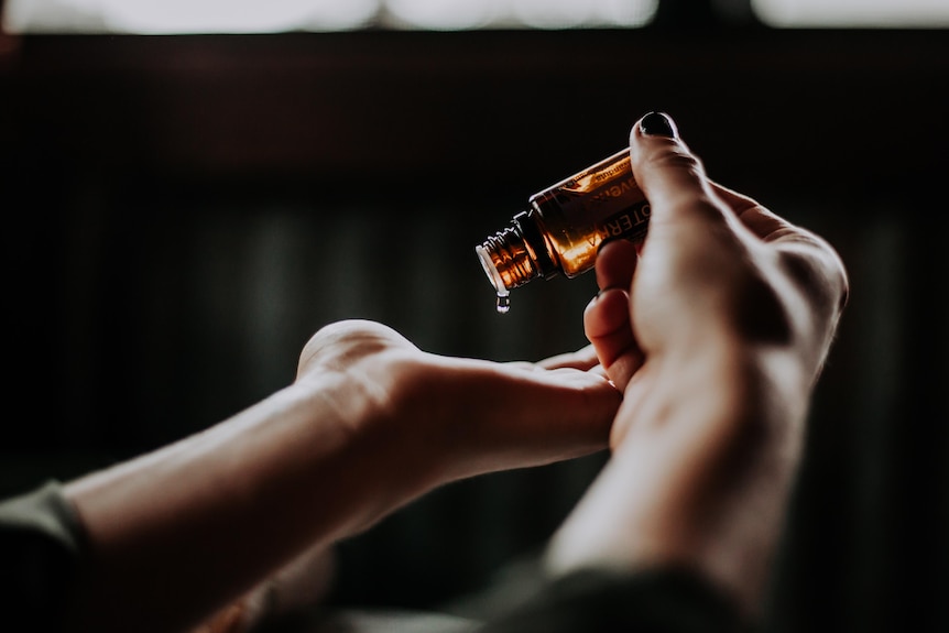 A woman puts a drop of essential oils on her palm.