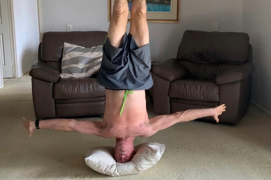 72-year-old Des Salmon doing a headstand in his living room.
