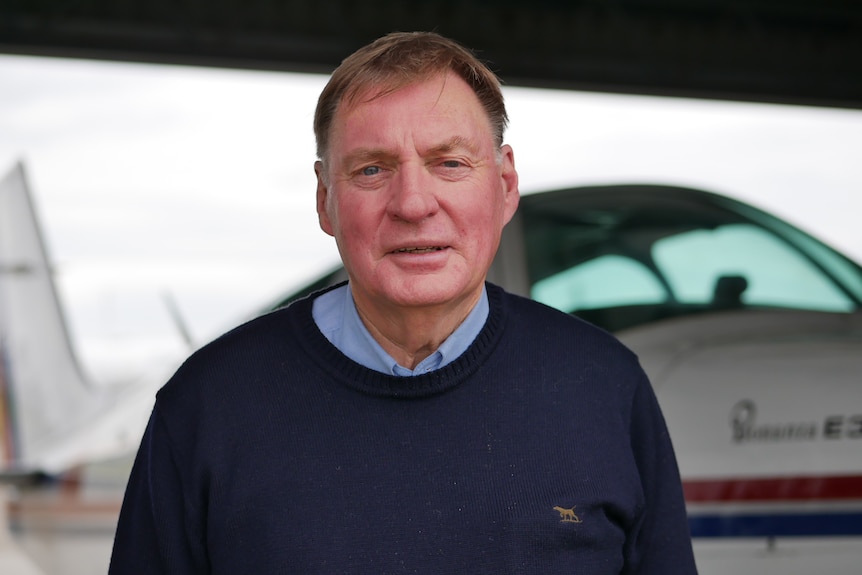 A man standing in front of a small aeroplane. 
