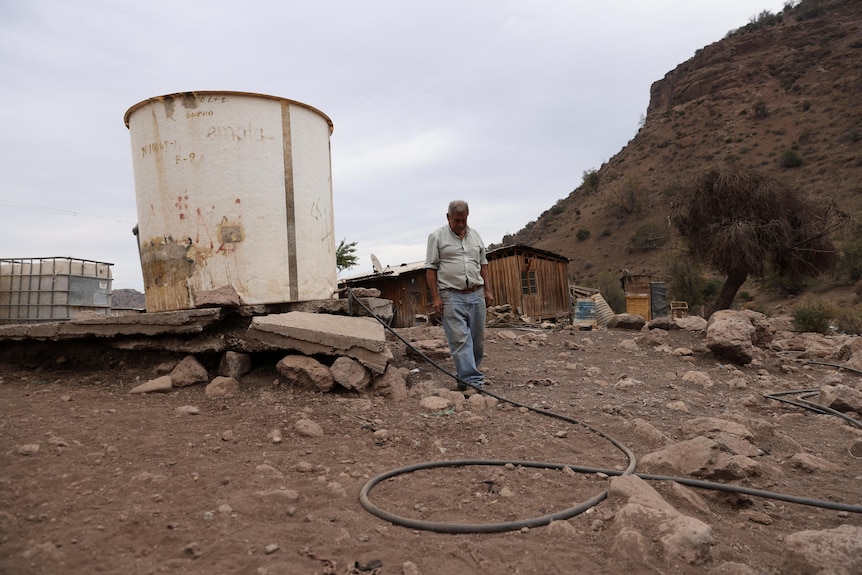 Un granjero se para cerca de un contenedor de agua que se usa para sus animales. 