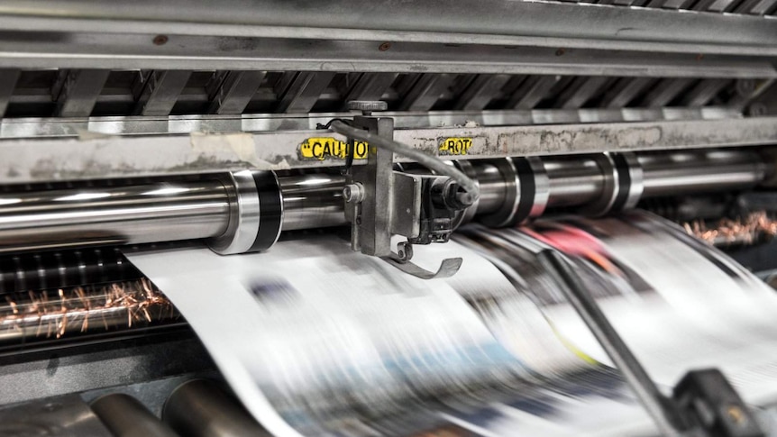 Printing press with newspaper being ejected from it.
