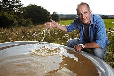 Grand Designs host Kevin McCloud runs his hand through a tank of water.