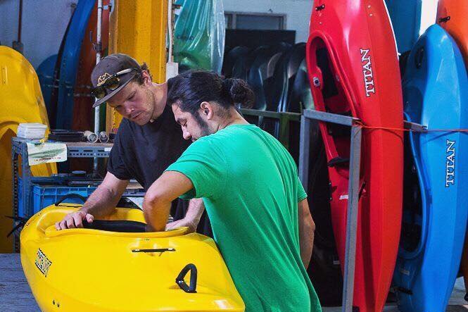 Two men examining kayaks.