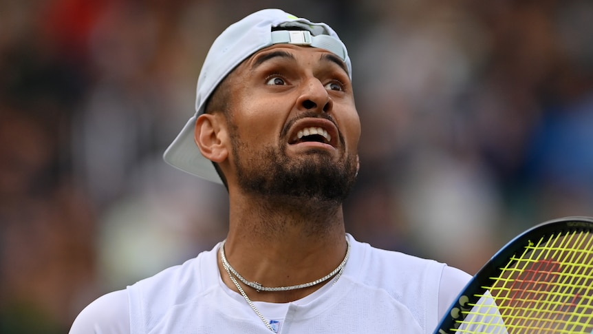 Close up of Nick Kyrgios speaking angrily with the chair umpire at Wimbledon. He has his hat on backwards