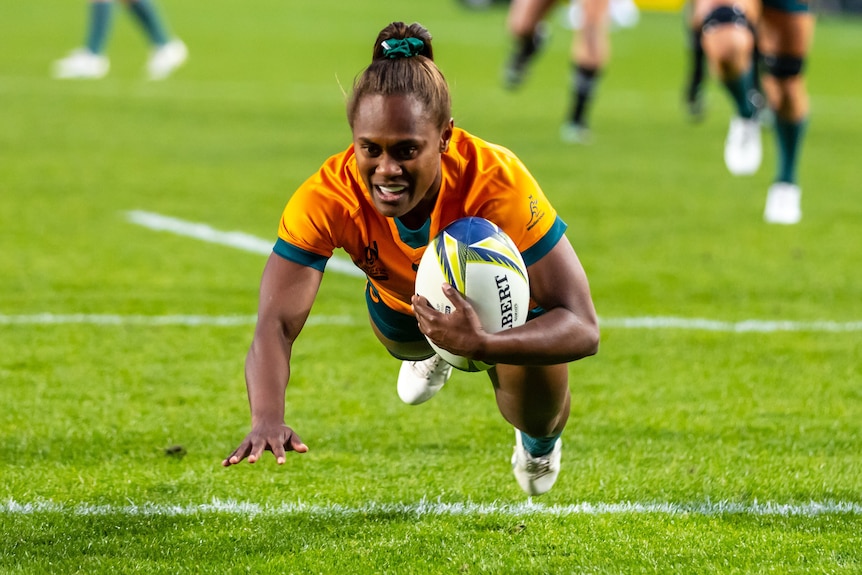 A Wallaroos player dives across the goal line to score a try at the women's Rugby World Cup.