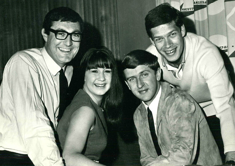 A black and white image of three young men and a young woman