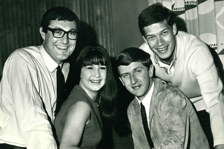 A black and white image of three young men and a young woman