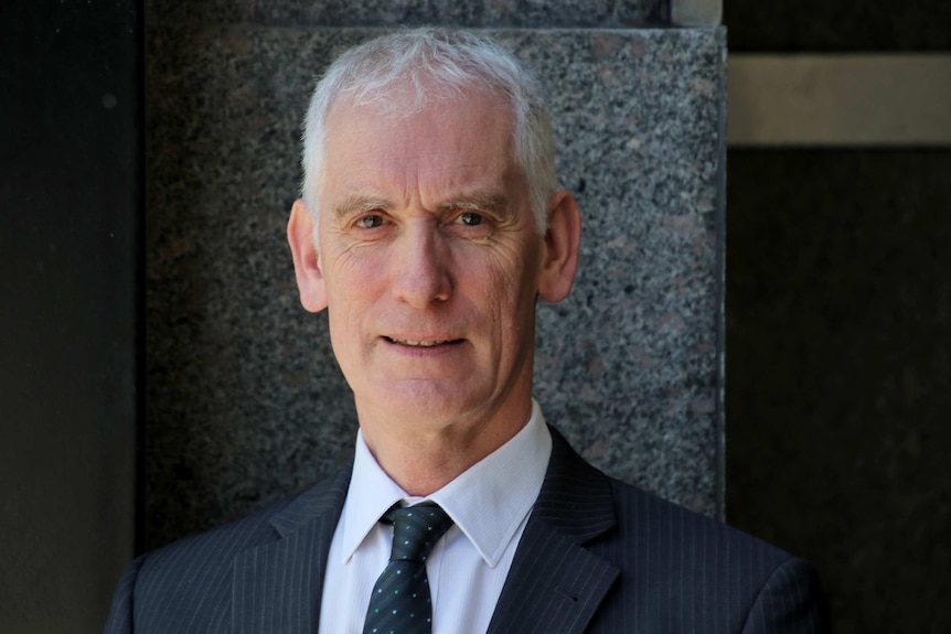 A close-up of Neil Morgan standing in front of building.