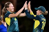 Two Australian players congratulate each other following the dismissal of a West Indian opponent.