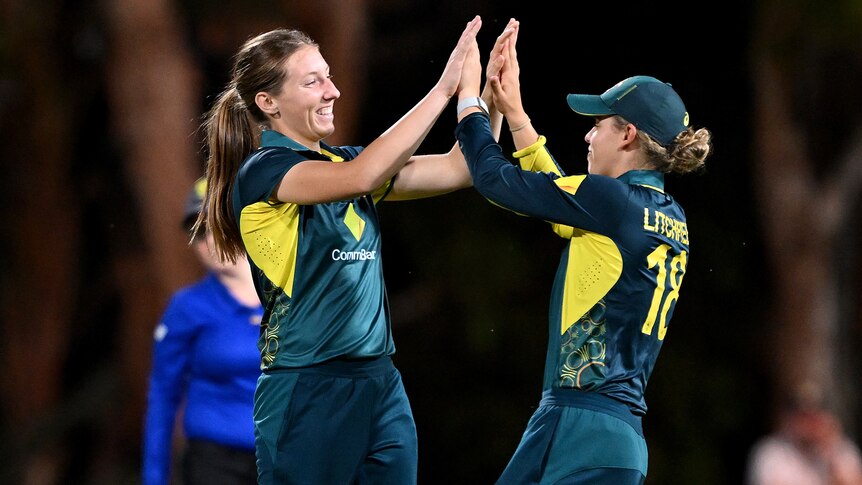 Two Australian players congratulate each other following the dismissal of a West Indian opponent.