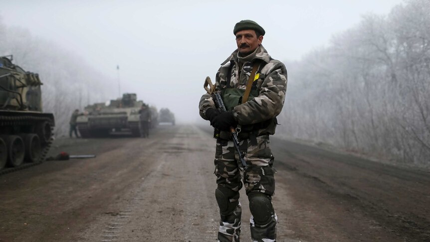 Ukrainian soldier stands in front of tanks