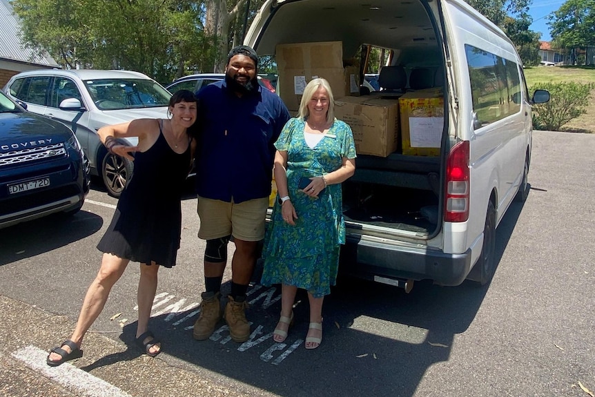 Lindsay, Steven and Kathy in front of a van with its boot open full of boxes. 