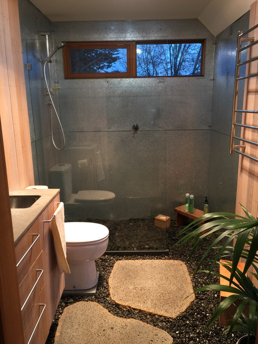 The bathroom with stainless steel walls and a pebble base floor.