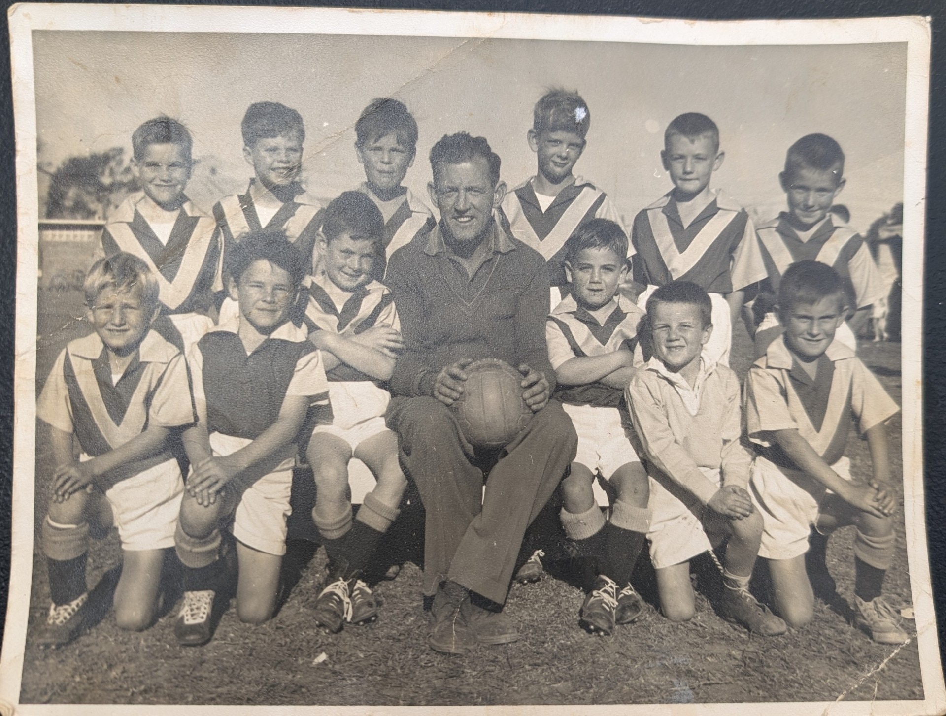 A black and white photo of a middle aged man and a junior soccer team