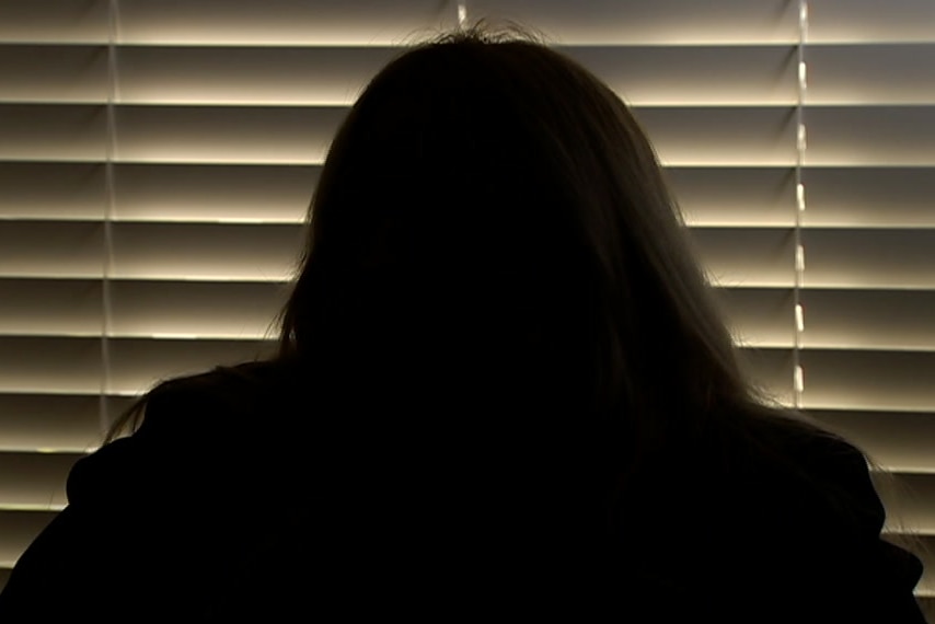 A woman's silhouette in front of a blind