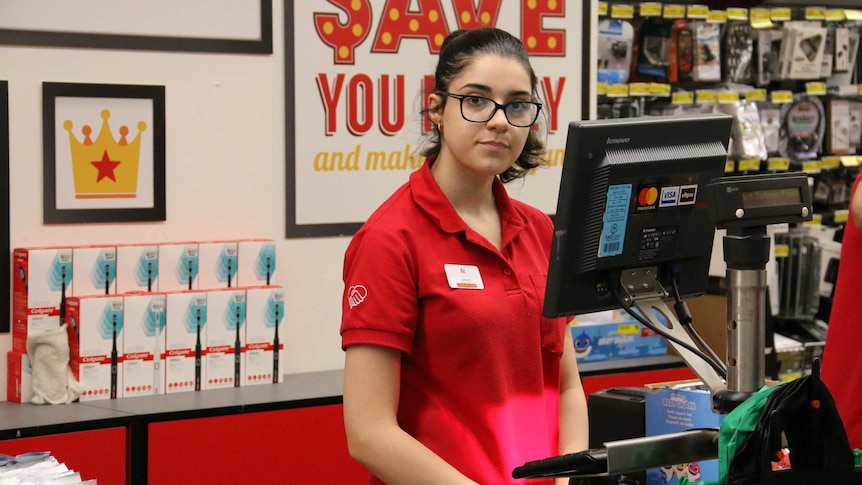 A young woman working at a shop counter.