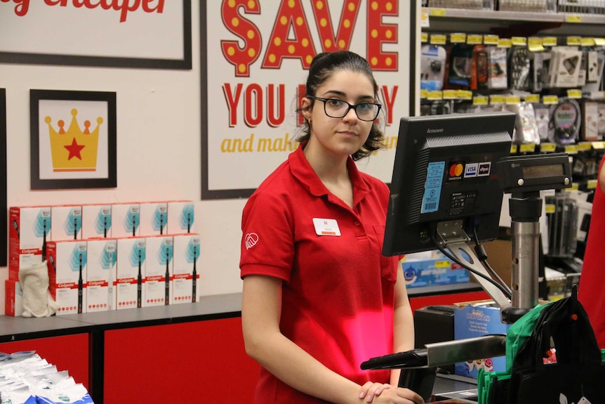 A young woman working at a shop counter.