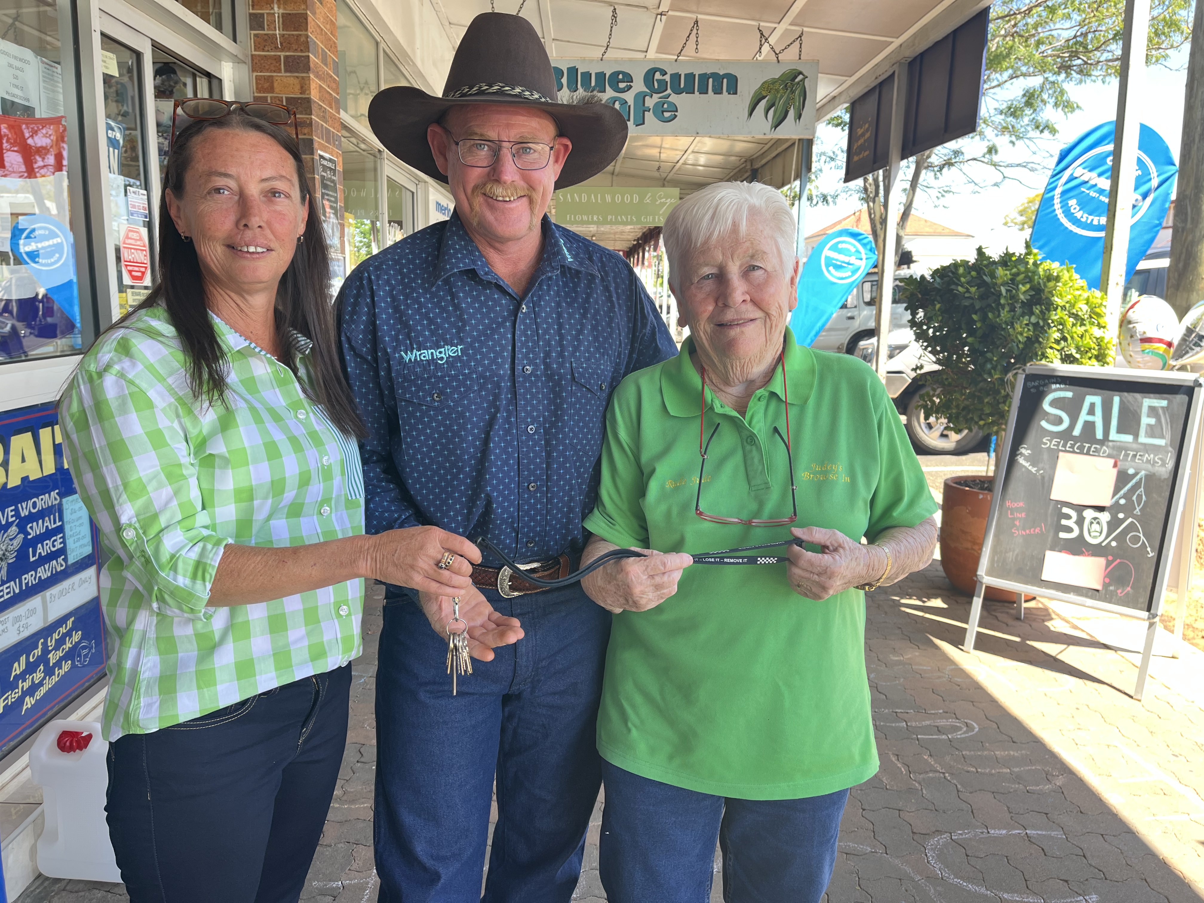woman in green shirt handing keys to couple