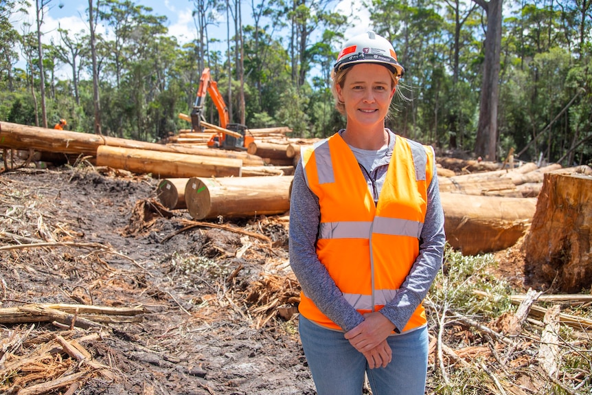 A woman standing near logged timber.
