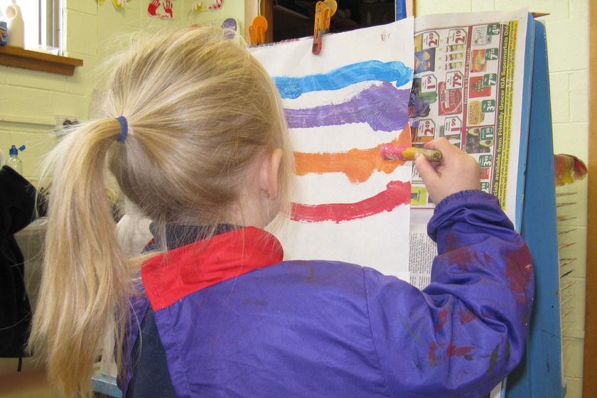 Unidentifiable five year old girl at a child care easel.