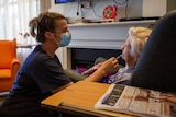 A nurse gives a covid test to an elderly lady