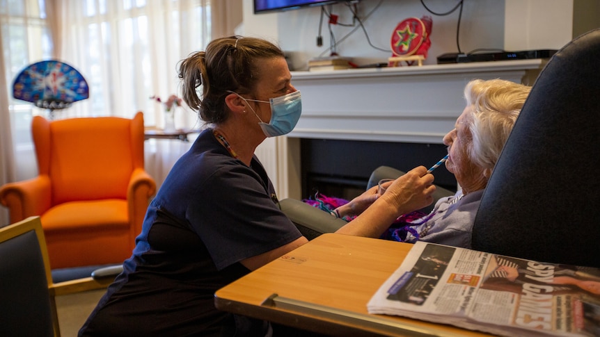 A nurse gives a covid test to an elderly lady