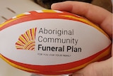 A yellow, orange and white mini rugby ball with branding of a funeral insurer
