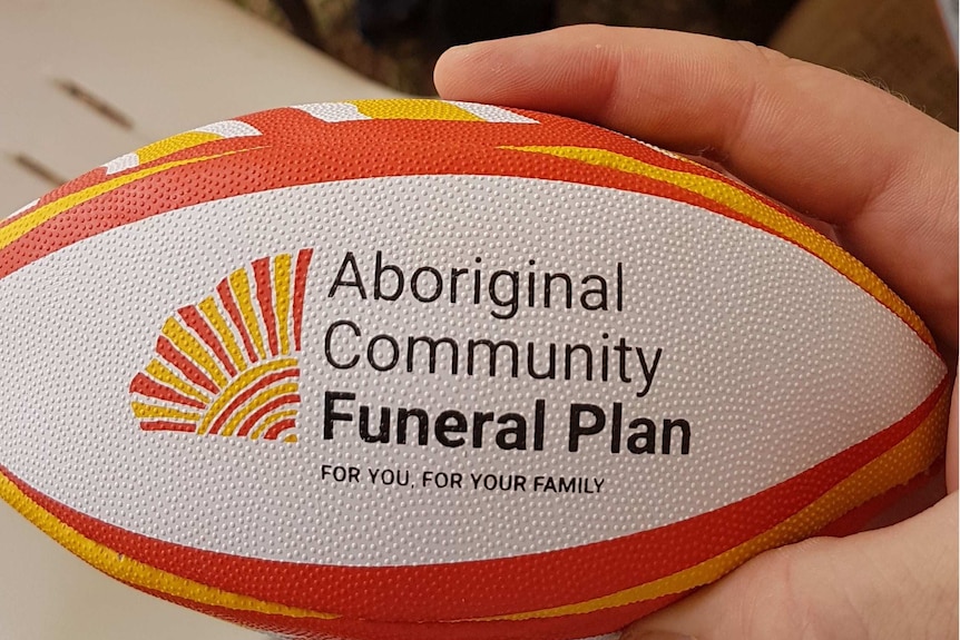 Una mini pelota de rugby amarilla, naranja y blanca con la marca de una compañía de seguros funerarios