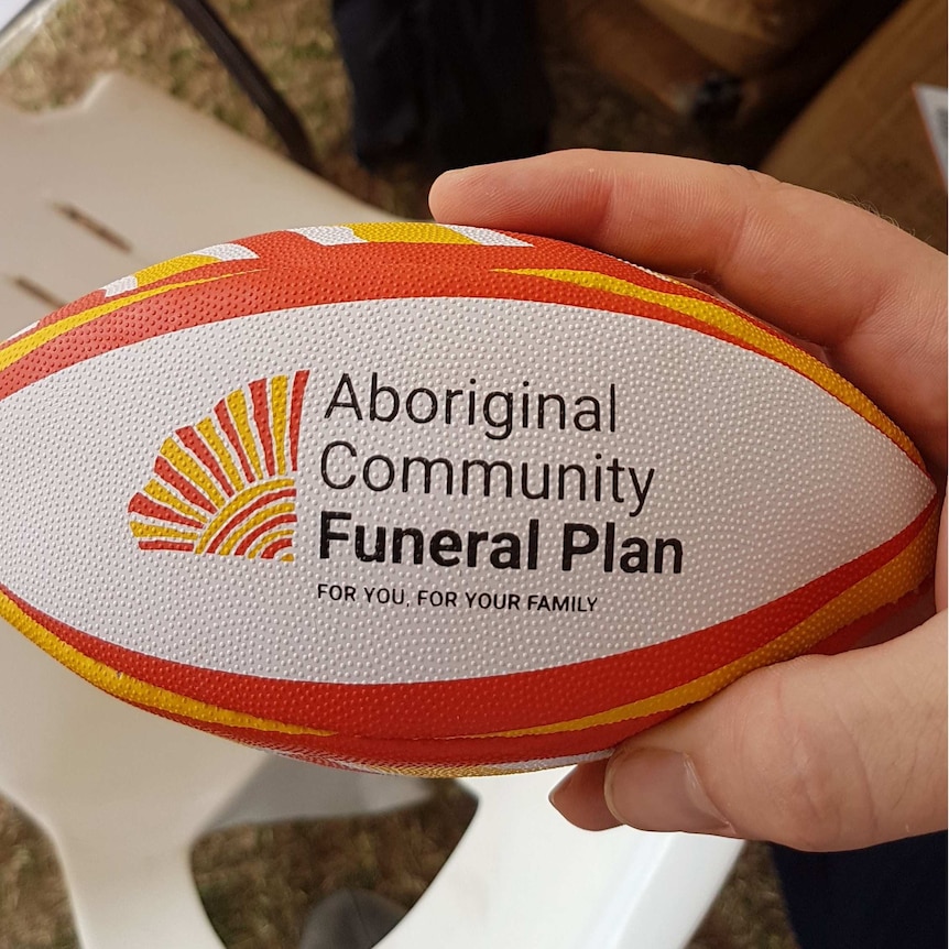 A yellow, orange and white mini rugby ball with branding of a funeral insurer