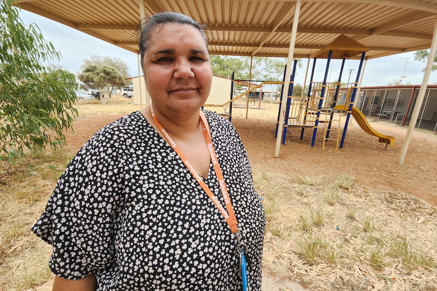 woman wearing black and white top and orange lanyard smiling in school playground