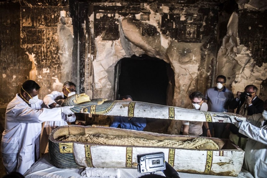 Egyptian archaeologists and council members opening sarcophagus