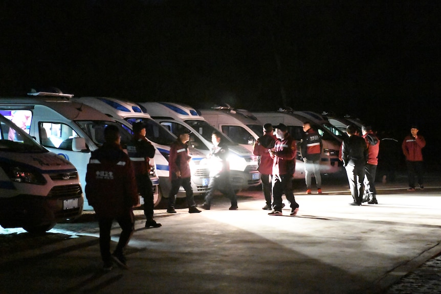 Emergency personnel and vehicles wait on standby in the night.
