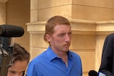 A man outside an Adelaide court surrounded by members of the media.