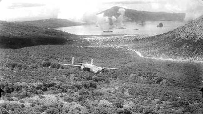 A B-25 Mitchell bomber aircraft flying low in a valley near Rabaul on return from a raid over Simpsin Harbour.