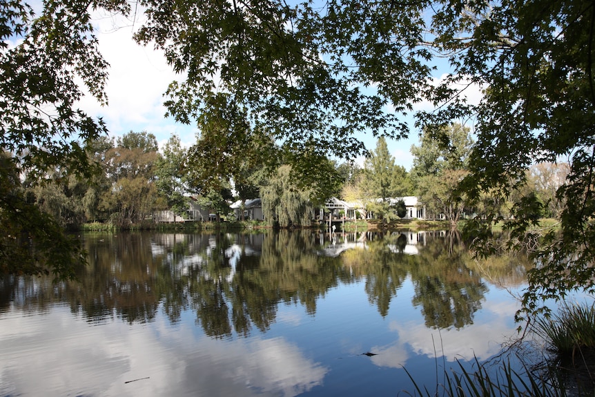 A house sits on a lake surrounded by trees