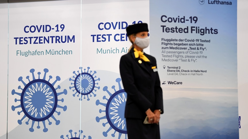 A masked flight attendant stands in front of a sign saying 'COVID testing' at a German airport in November, 2020.