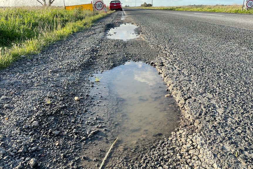 Potholes with water pooling in them along a highway.