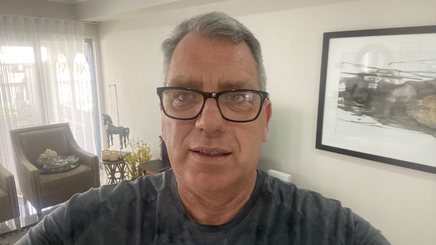 A profile image of a man, wearing glasses, in his living room