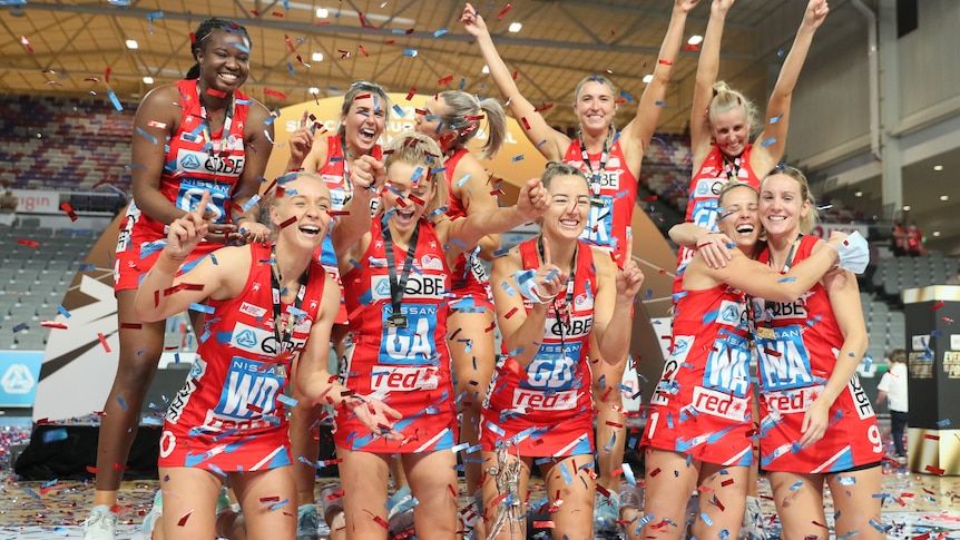 Les joueurs des Swifts lancent des confettis rouges et bleus en l'air et posent avec leurs médailles et leur trophée