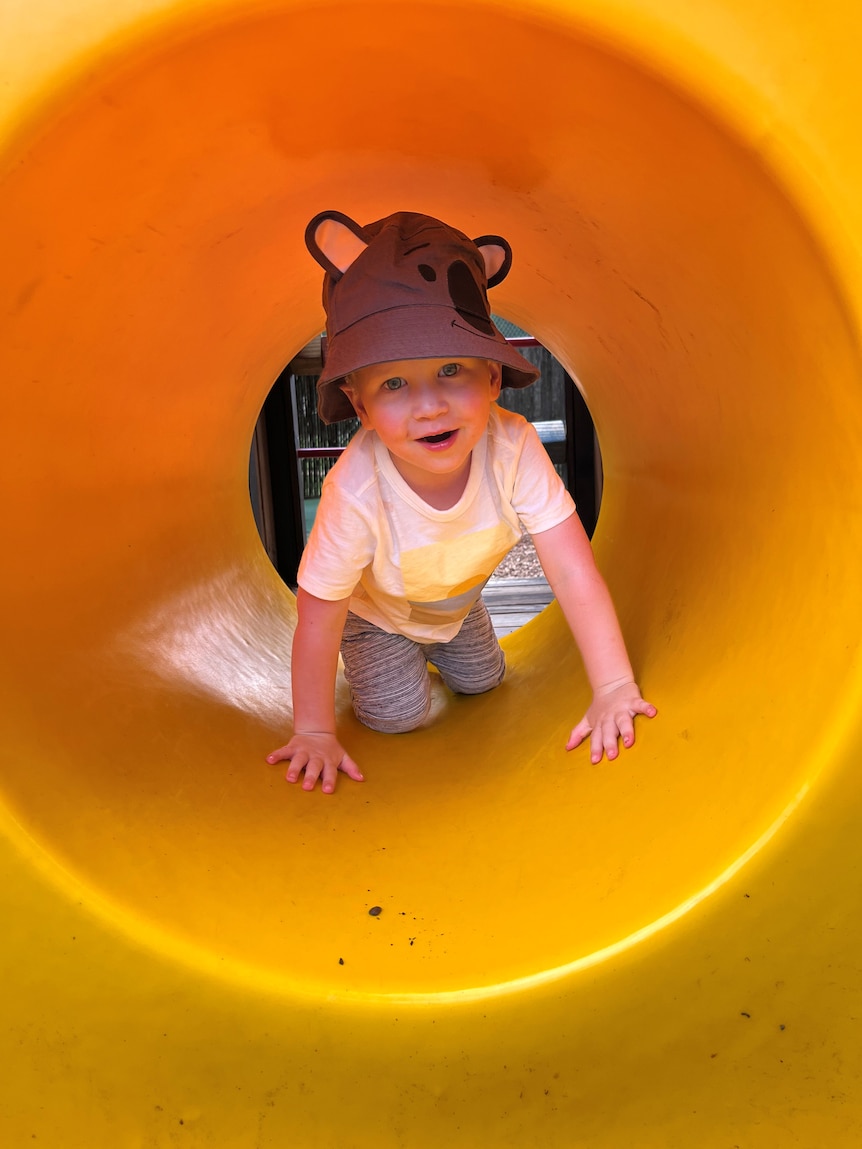 A young boy plays in a playground tunnel.