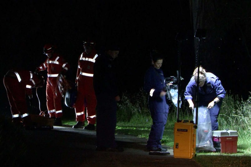 Detectives investigating an alleged crime scene at night.