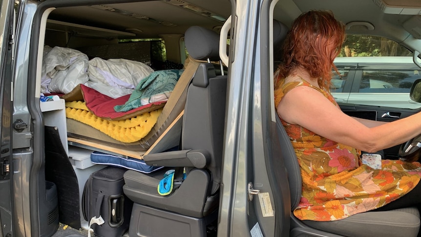 woman sitting in her van with possessions in the back 