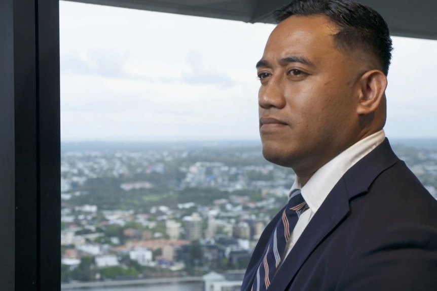 Close up profile image of a Samoan mans face as he stares out the window overlooking Brisbane River and city.