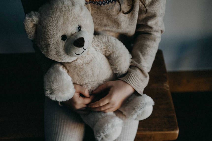A child holds her teddy bear